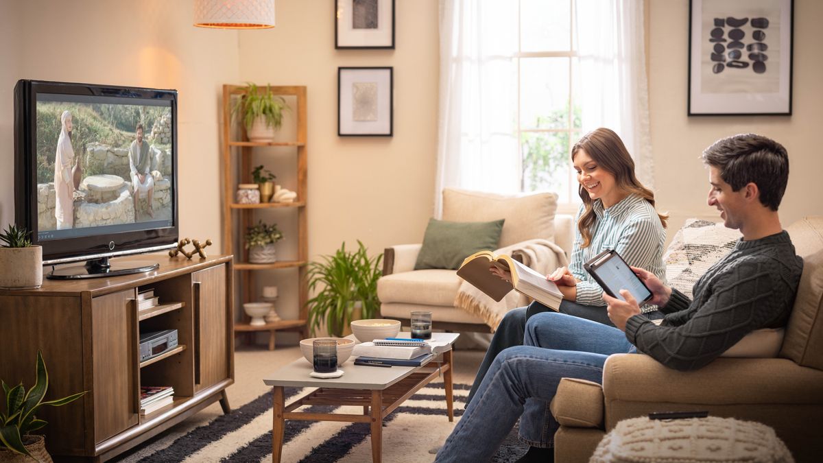 The same couple happily following along in their Bibles as Episode 3 of “The Good News According to Jesus” plays on their TV.