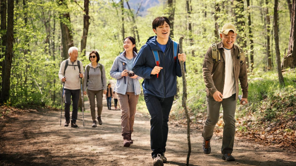 The young brother from a previous image enjoys a hike with his friends.