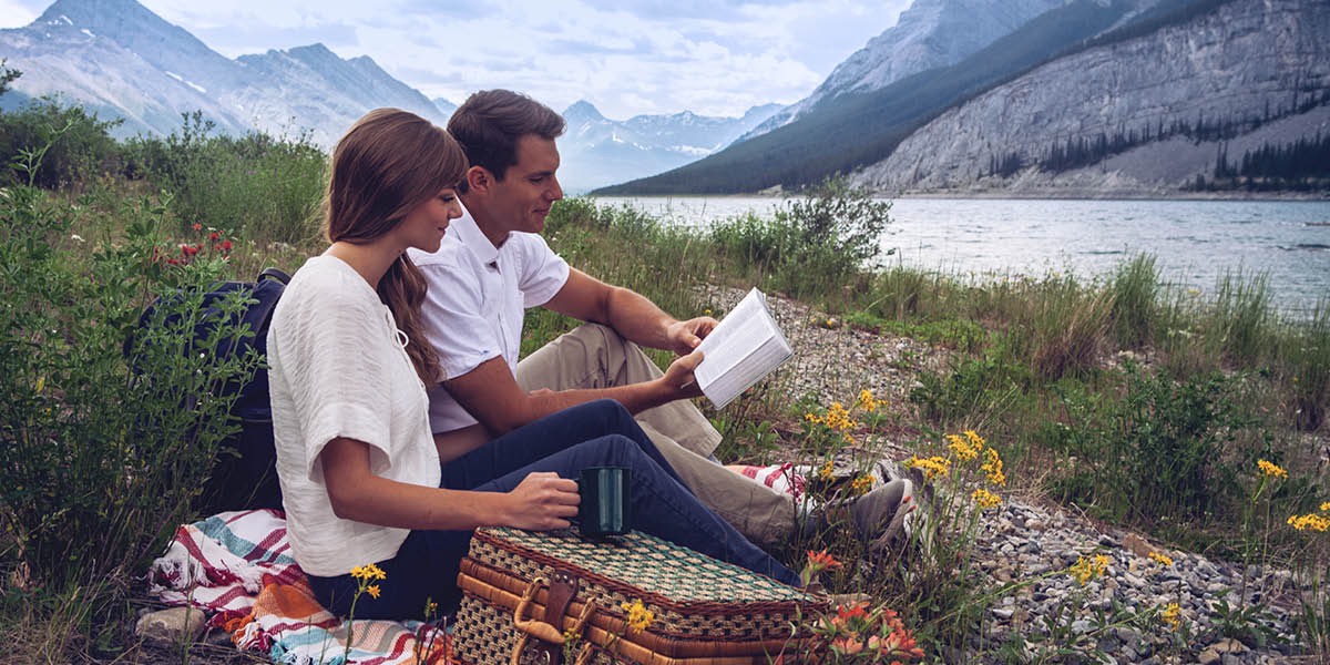 A couple reads the Bible while on a picnic