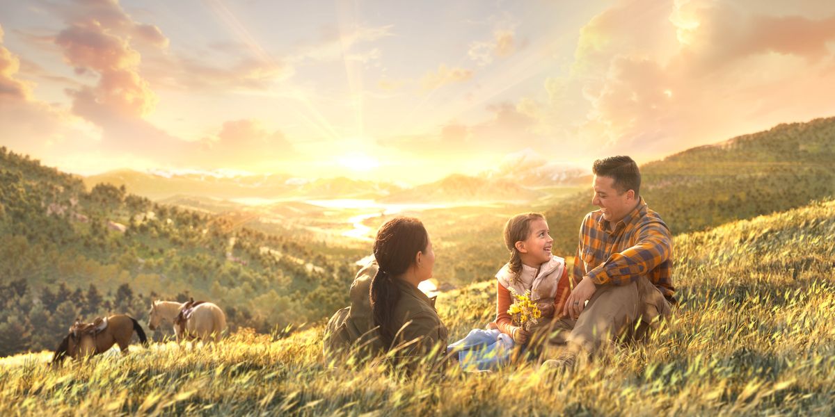 A family laughing together as they sit atop a hill on a paradise earth. Horses graze nearby.