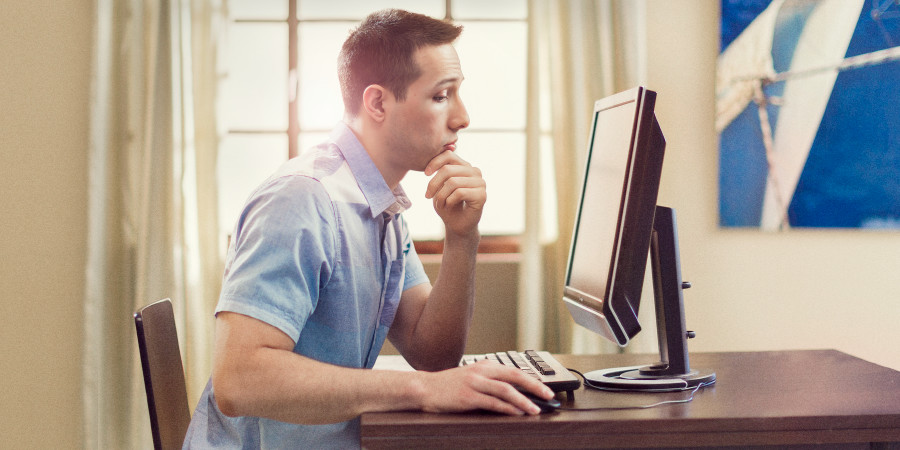 A man looks contemplatively at his computer monitor