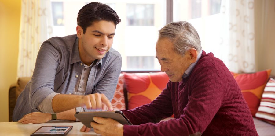 A younger brother helps an older brother with his electronic device