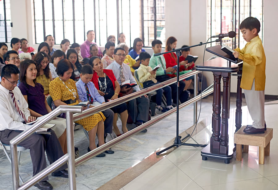 Un niño cumpliendo con su asignación de lectura bíblica en la Escuela del Ministerio Teocrático