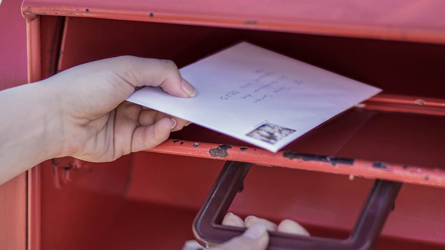 Una hermana deposita una carta en un buzón de correo
