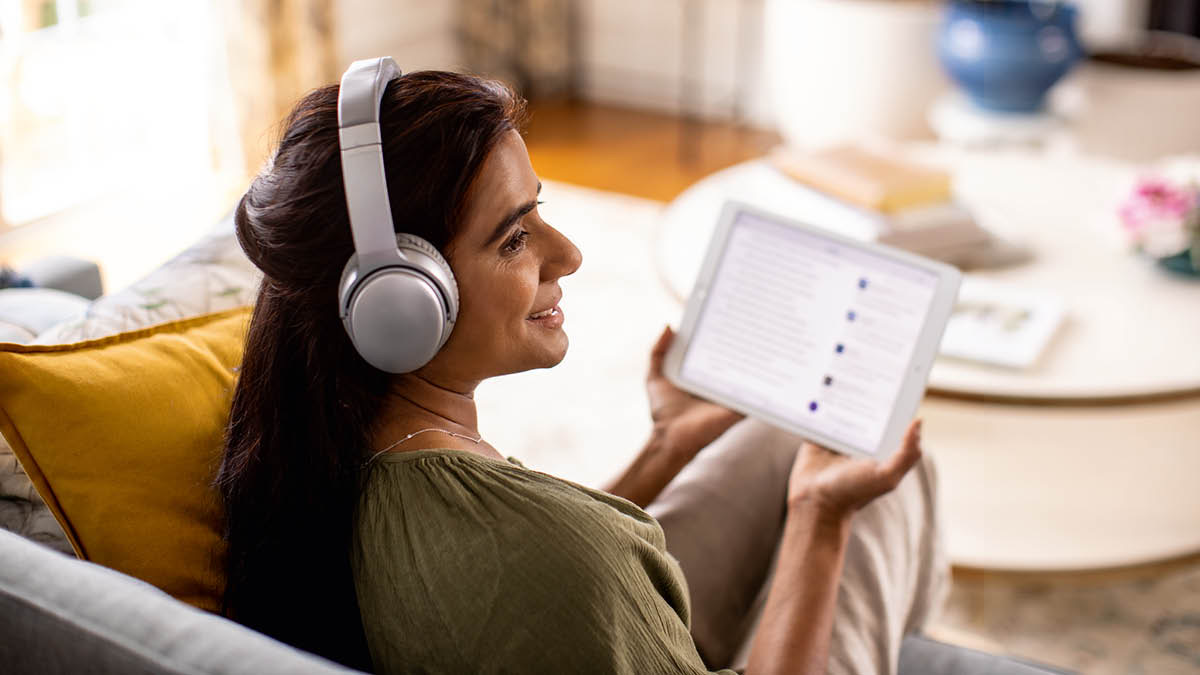 Una hermana lleva puestos unos audífonos o auriculares y escucha una grabación de audio en su tableta.