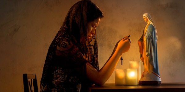 زنی در کلیسای کاتولیک در حال دعا به مجسمه مریم