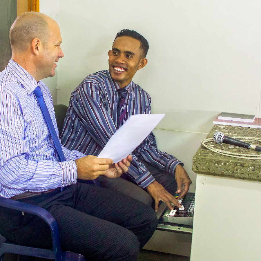 بنجامين در كنار دستگاه صوتی سالن جماعت با يكی از برادران محلّی صحبت می‌كند