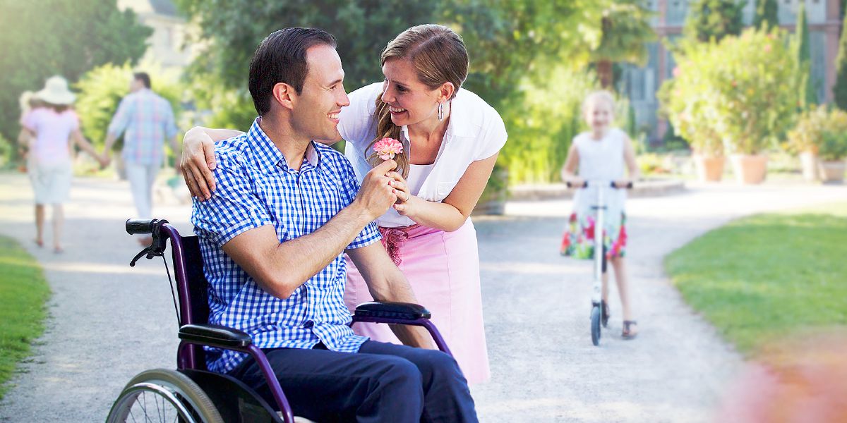 Un homme dans un fauteuil roulant en train de donner une fleur à sa femme