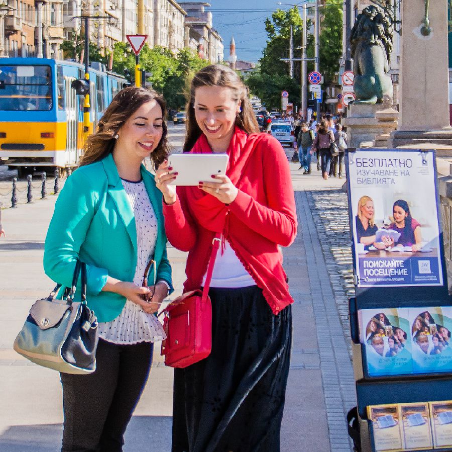 Sestra stoji pored pokretnog stalka za literaturu i propovijeda jednoj ženi