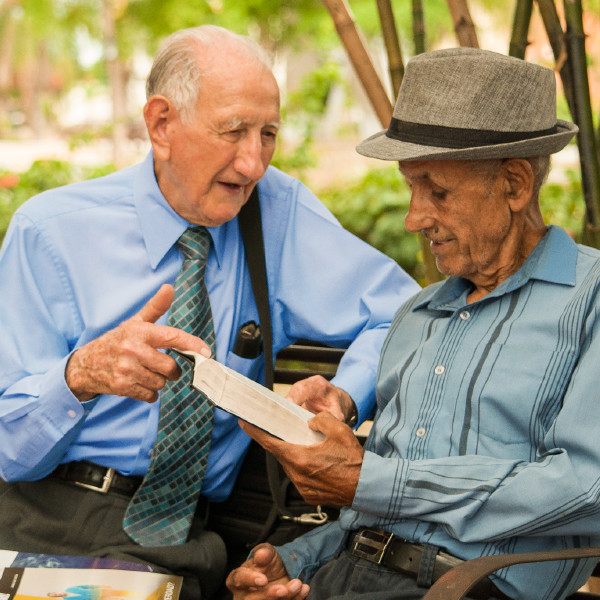 Egy idős testvér a parkban egy padon ülve beszélget a Bibliáról egy férfival