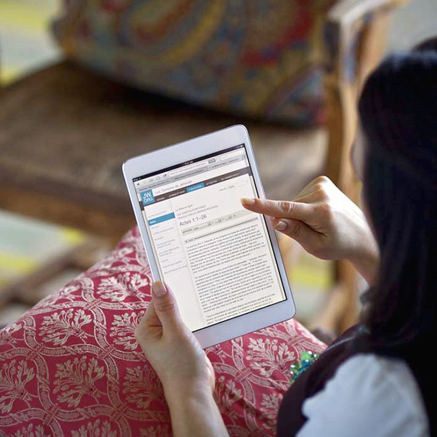 Seorang wanita membaca Alkitab online di jw.org dengan tabletnya.