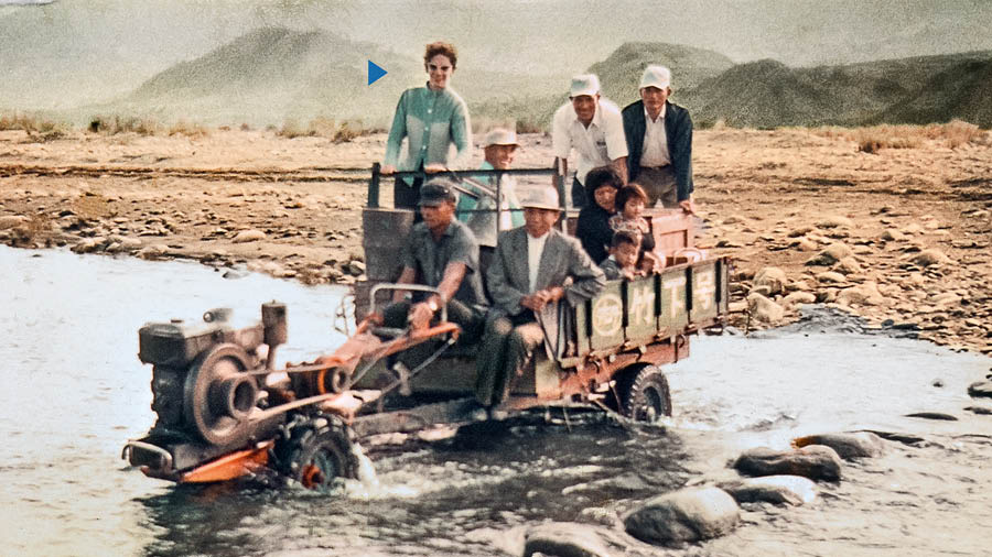 Kathleen, Harvey, dan beberapa orang lain menaiki kendaraan yang dibuat seadanya untuk menyeberangi sungai yang dangkal.