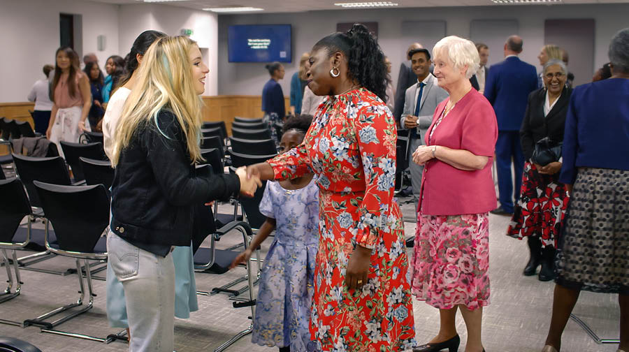 A scene from the video “Help Your Bible Students to Attend Meetings.” Sisters warmly greet Jade after a congregation meeting.