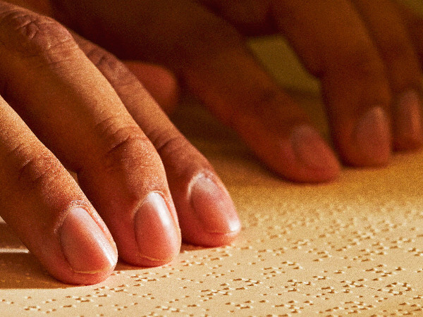 Una persona legge la Torre di Guardia in braille