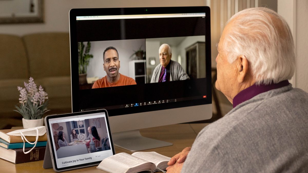 Un anziano fa una visita pastorale a un fratello in videoconferenza. L’anziano ha la Bibbia aperta e sul suo tablet si vede il video “Coltiviamo la gioia in famiglia”.