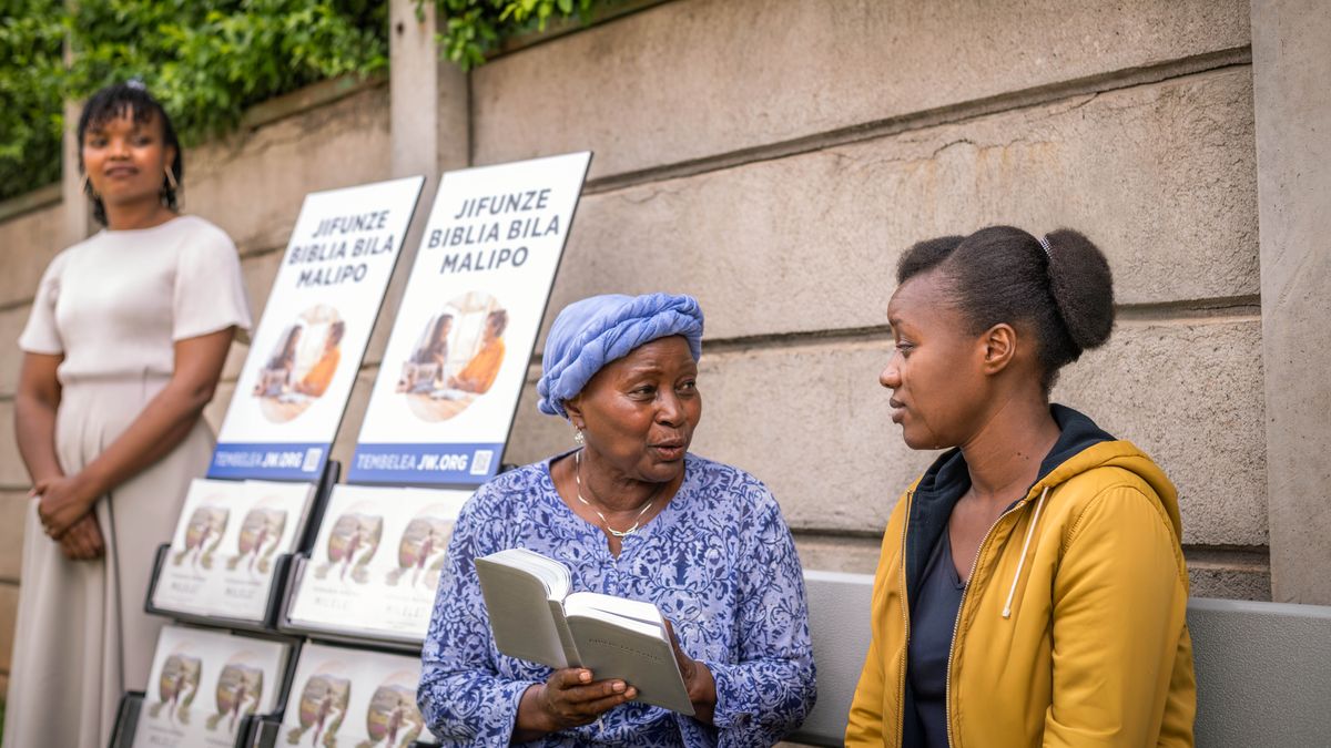 Una sorella anziana partecipa alla testimonianza con l’espositore. Legge un passo biblico a una giovane donna che ha il viso rigato dalle lacrime.