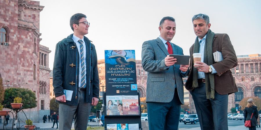 Testimoni di Geova predicano a un uomo vicino a un espositore mobile