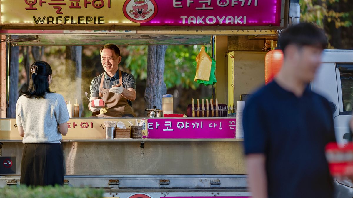 푸드 트럭에서 장사를 하는 남자가 음식을 손님에게 줍니다.
