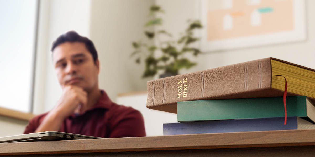 Muntu mulume welangana meji mutangile Bible ne mikanda mikuabu idi pa mêsa.