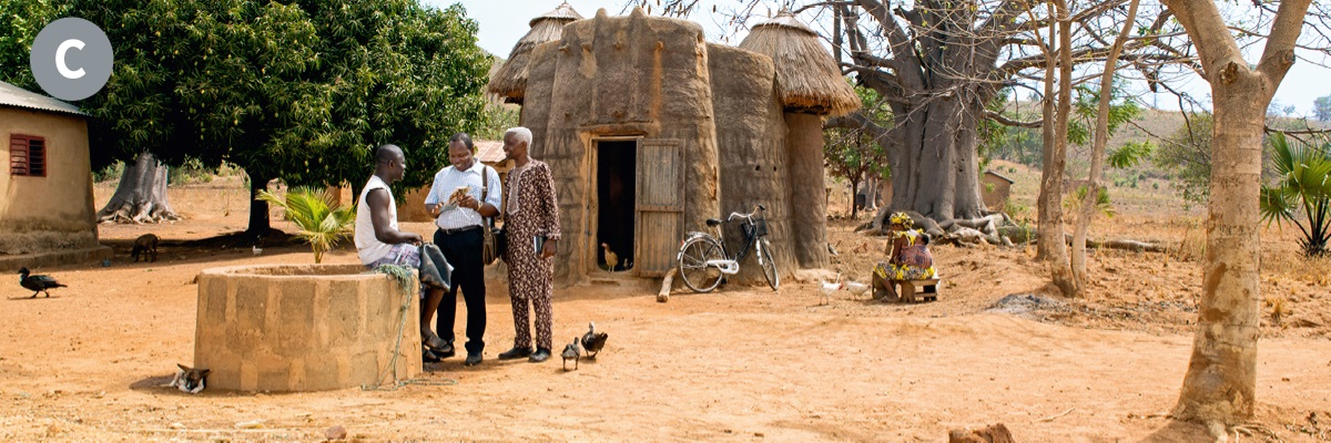 C. Divi Jehovas liecinieki sludina vīrietim kādā Beninas ciemā.