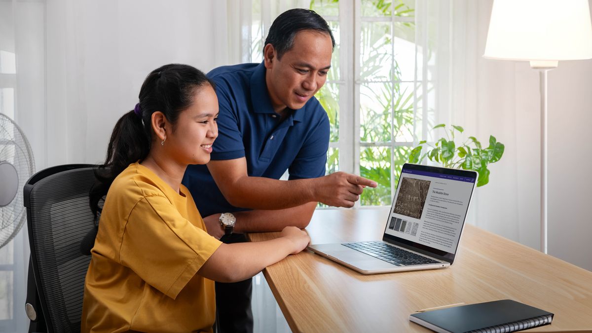 Seorang bapa dan anak perempuannya yang remaja menggunakan komputer untuk melihat laman web sebuah muzium.