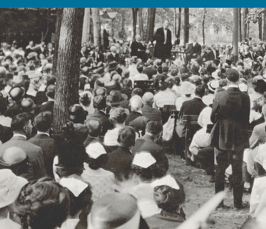 Joseph Rutherford spreekt op het congres van de Bijbelonderzoekers in 1919 een groot publiek toe dat onder bomen zit
