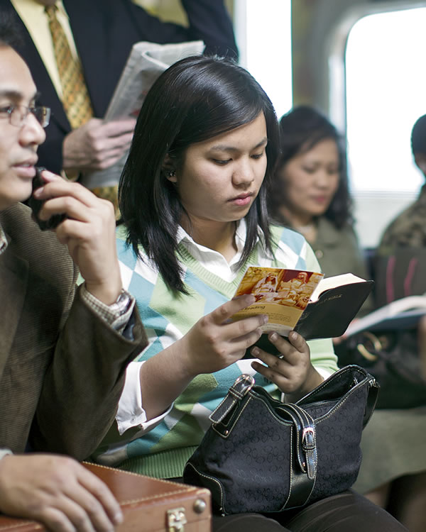 Een vrouw in een trein die de Bijbel leest