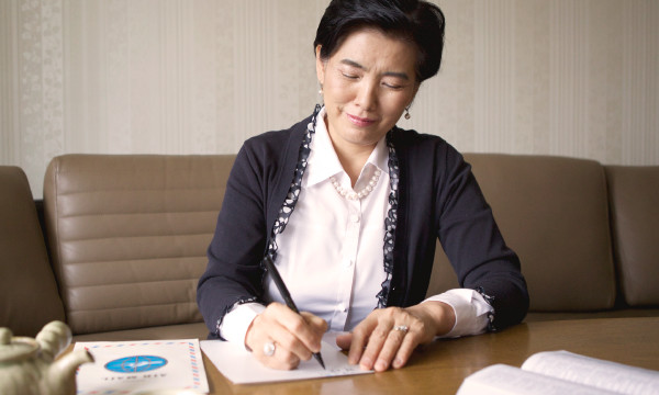 Een oudere vrouw die een brief schrijft