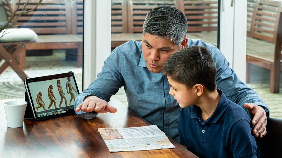 Een vader bespreekt met zijn zoon de brochure ‘Vijf belangrijke vragen over het ontstaan van het leven’.