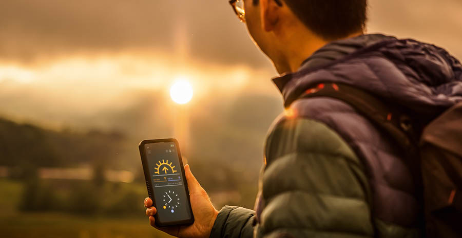 En mann bruker telefonen sin for å sjekke tidspunktet for solnedgangen.