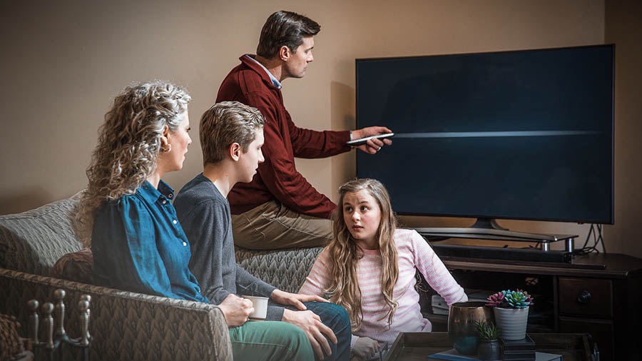 Un famia Testigu ta sintá den sala i e tata ta paga e televishon