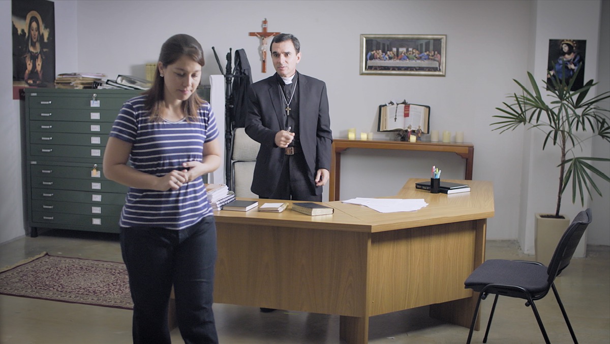 Cena do vídeo ‘Saiam de Babilônia, a Grande!’. Uma estudante da Bíblia dá as costas para o padre depois de pedir demissão do emprego que tinha na igreja.