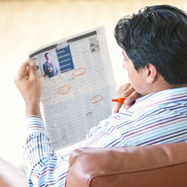 Um homem procurando emprego num jornal