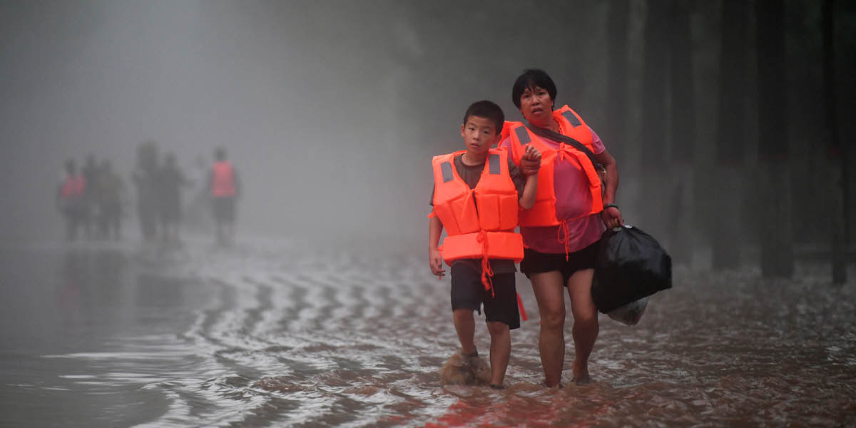 Uma mulher e um menino andando em uma rodovia inundada.