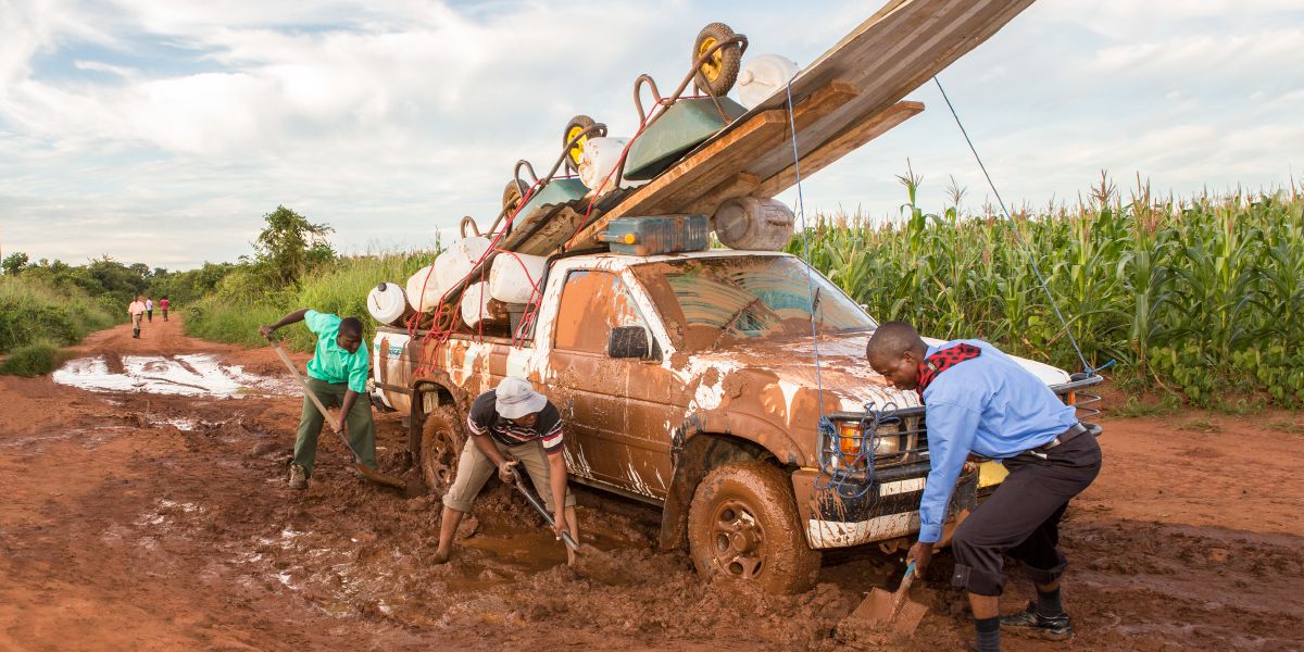 Homens trabalhando juntos para tirar uma caminhonete atolada na lama