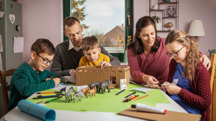 O familie cu trei copii construiește o machetă a arcei lui Noe în care pun animale.