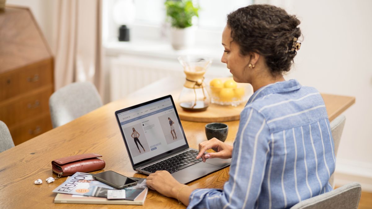 O soră caută pe internet o ținută modestă. Lângă computer are și câteva reviste de modă.