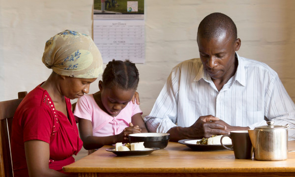 Мужчина с женой и дочерью молится перед едой