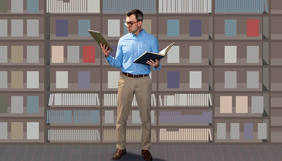 Этот же мужчина сравнивает информацию из книги, которую взял с полки, с информацией в планшете