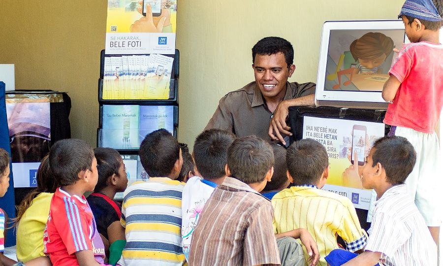 Në një stendë literature në Suai, Timori Lindor, fëmijët shohin video nga rubrika ‘Bëhu mik i Jehovait’