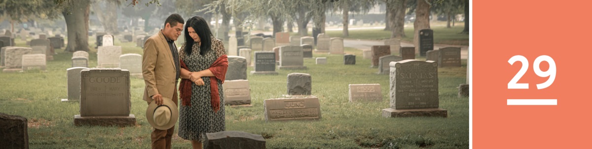 Lección 29. Una pareja orando delante de una lápida en un cementerio.