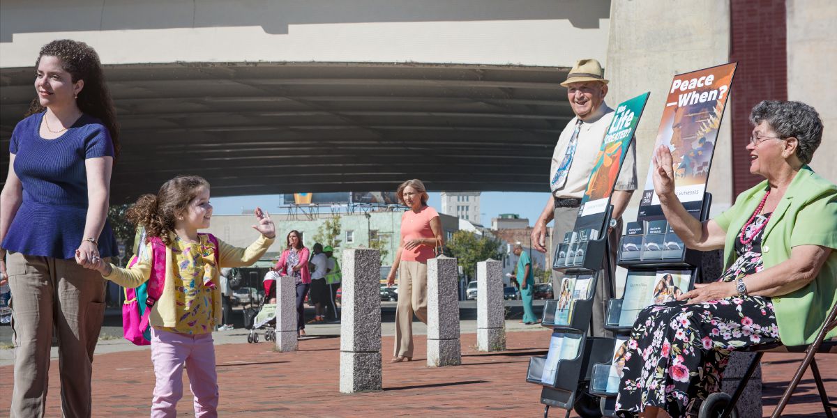 Sergio y Olinda ofrecen publicaciones bíblicas a las personas cerca de una parada de autobús