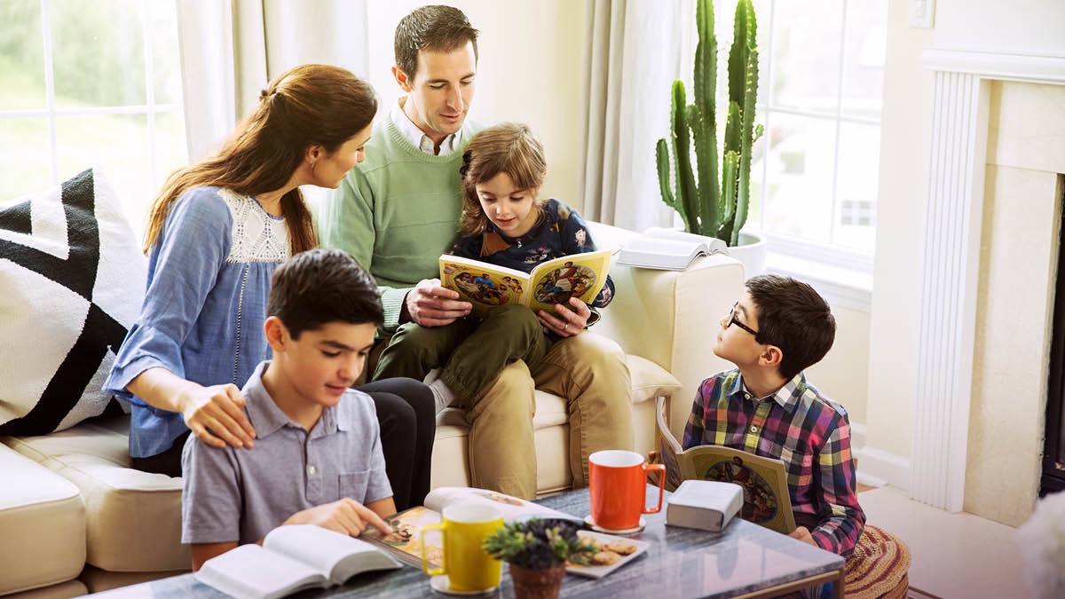 Un matrimonio estudia con sus hijos el libro Aprendamos del Gran Maestro