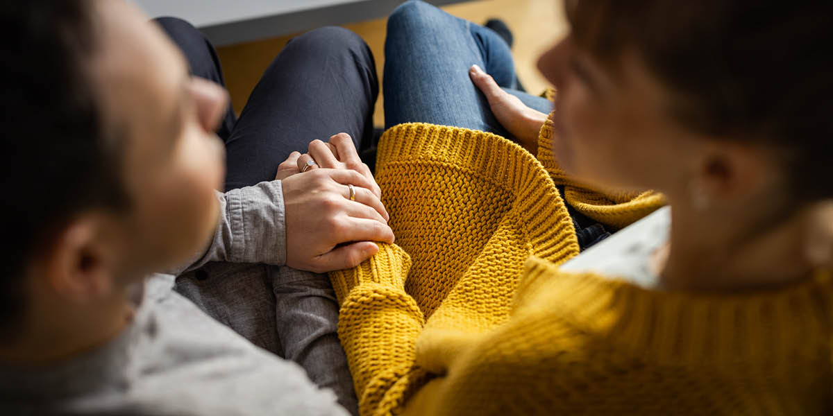 Monna le mosali ba lutse fatše ba tšoarane ka matsoho baa bua.