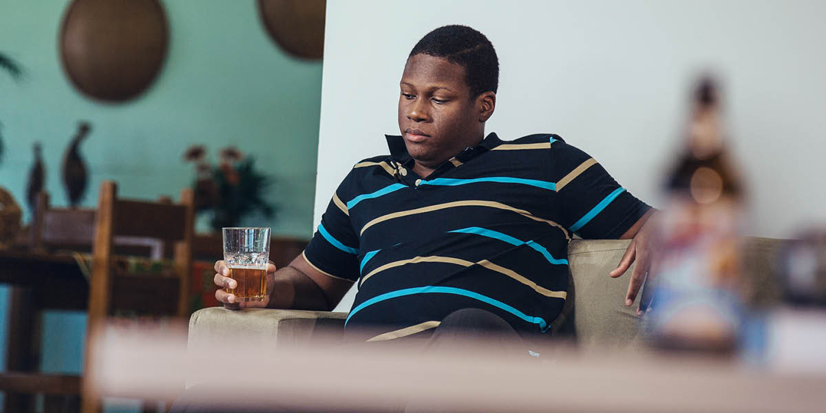 ’Mè o shebile khalase e tšetseng joala boo a ntseng a bo noa ha a lutse a le mong ha hae.