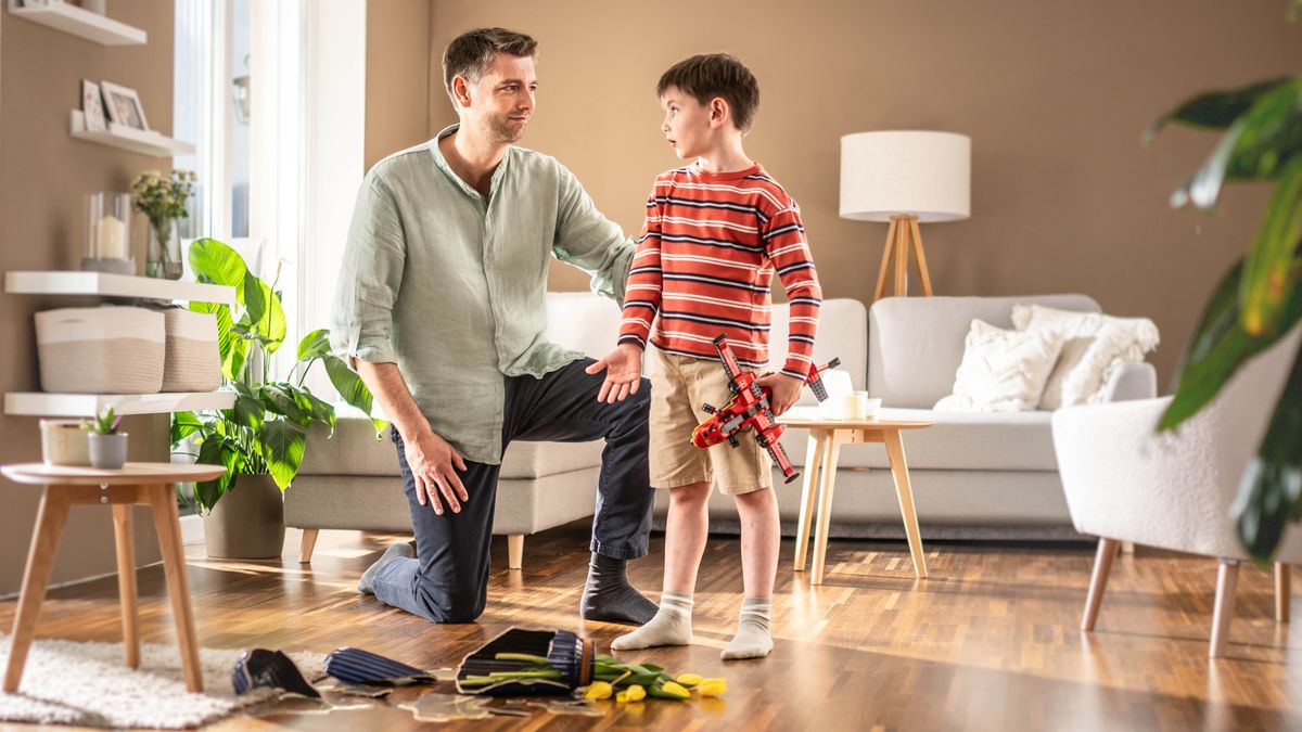 Ntate o mametse ka mamello ha moshanyana oa hae a ntse a mo hlalosetsa hore o pshatlile vase ea lipalesa ka phoso ha a ntse a bapala ka sefofane sa hae.