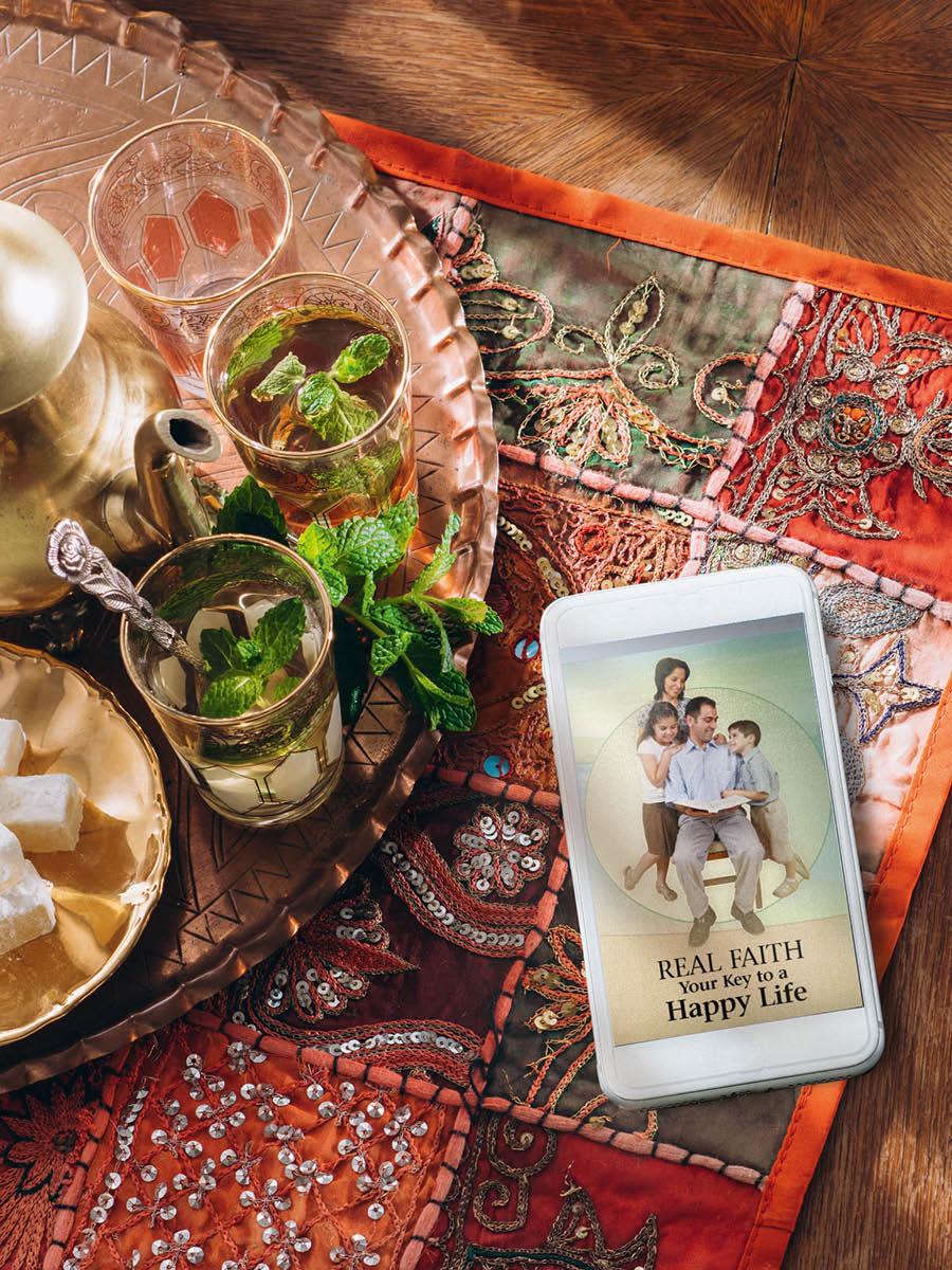 Fono e lutseng pel’a likopi tse peli tsa kofi. Bukana ea ‘Real Faith​—⁠Your Key to a Happy Life’ e hlahile ka fonong eo.