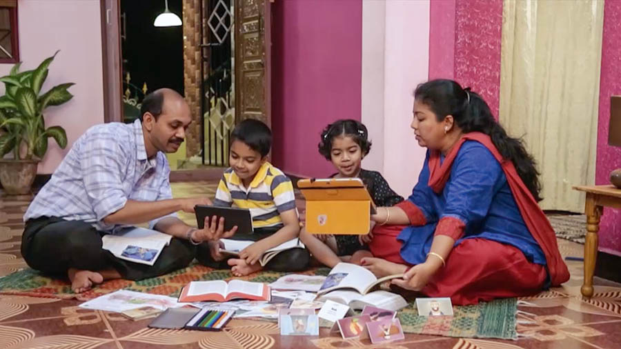 Gambar tina vidéo ’Ngawangun Imah nu Weweg—Jaga Budak Sadérék ti ’Hal-Hal anu Jahat.’’ Kolot ngajar barudakna maké buku ’Mendengar kepada Guru yang Agung’ jeung bahan séjénna.