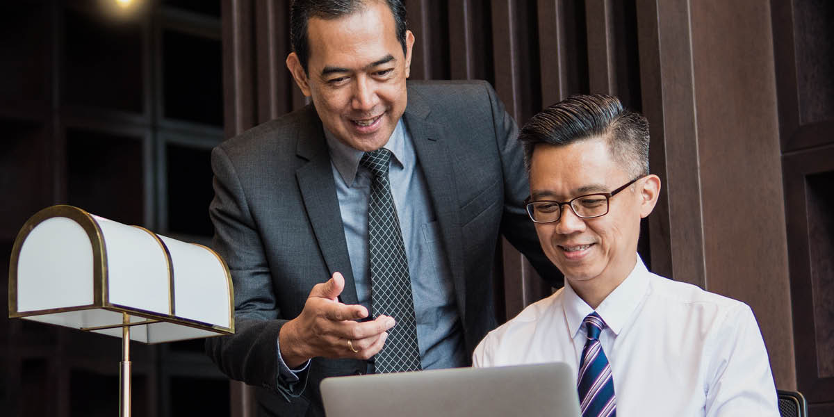 Saurang pangusaha ngadiktékeun surat sina diketik ku sékertarisna dina laptop.