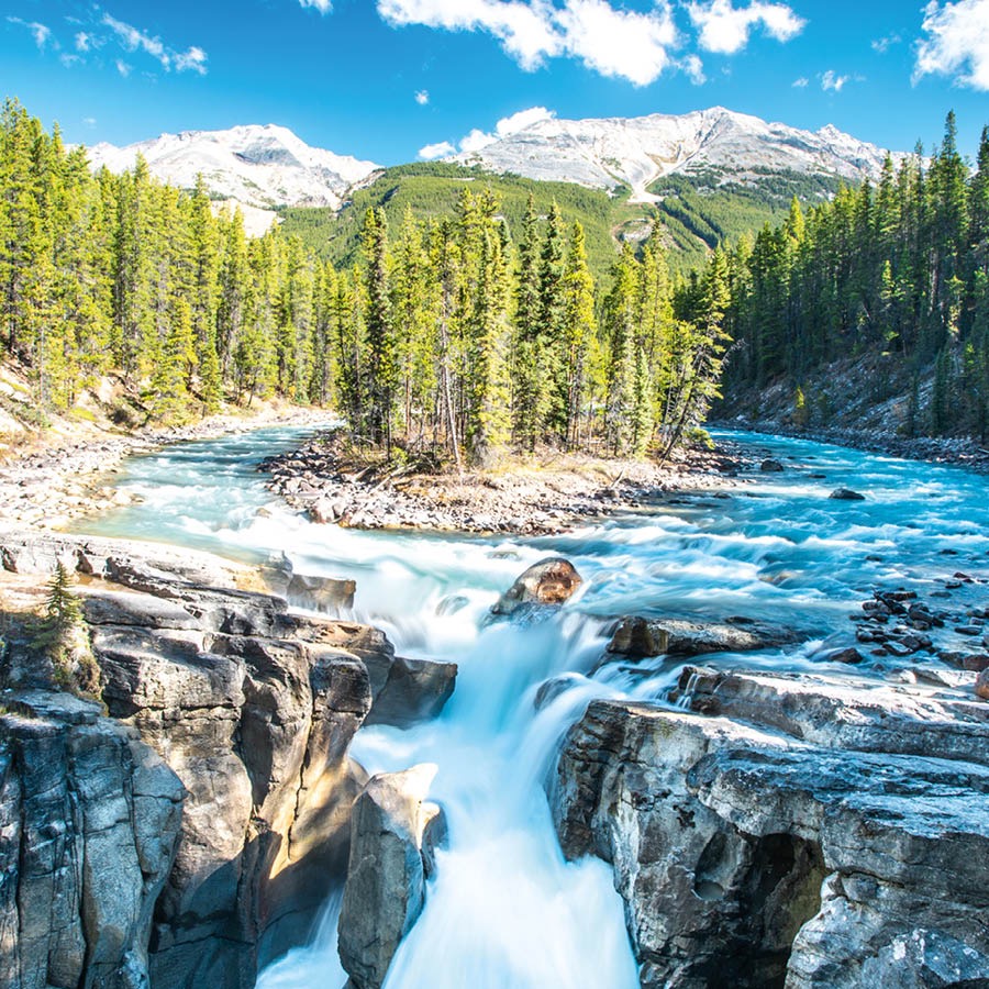 Cai walungan nu ngocor kana curug. Walungan éta dikurilingan ku gunung-gunung nu pinuh ku salju jeung leuweung.